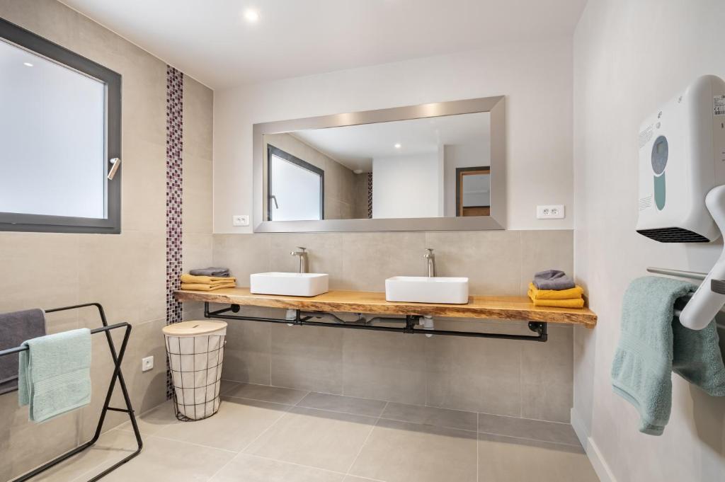 a bathroom with two sinks and a mirror at L&#39;Attrape Rêves in Villelongue-dels-Monts