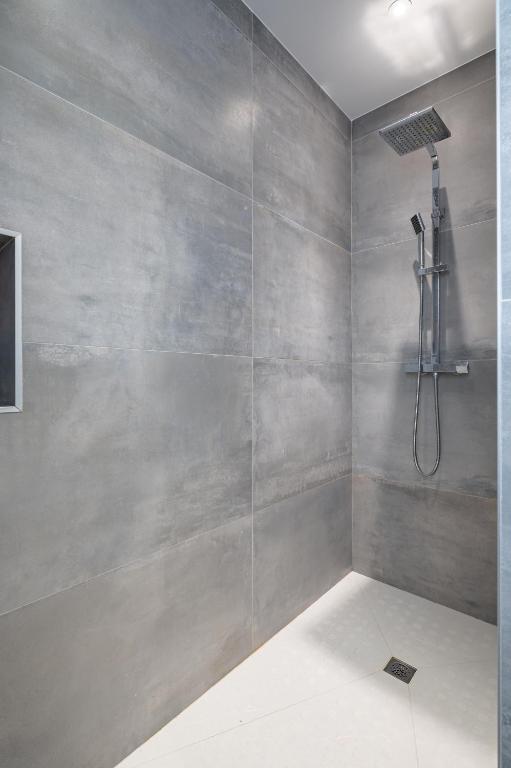 a gray bathroom with a shower and a shower head at L&#39;Attrape Rêves in Villelongue-dels-Monts