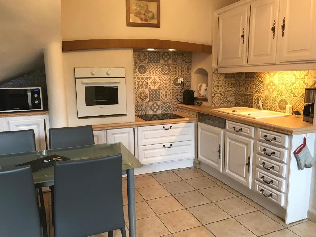une cuisine avec des armoires blanches et une table avec des chaises dans l'établissement Gîte Maison de Sophie, à Saint-Aignan