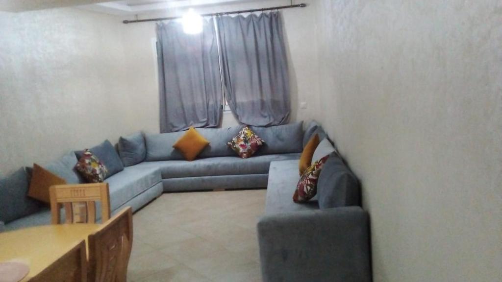 ein Wohnzimmer mit einem blauen Sofa und einem Tisch in der Unterkunft Jnane Eddalya Bouznika C23 in Bouznika