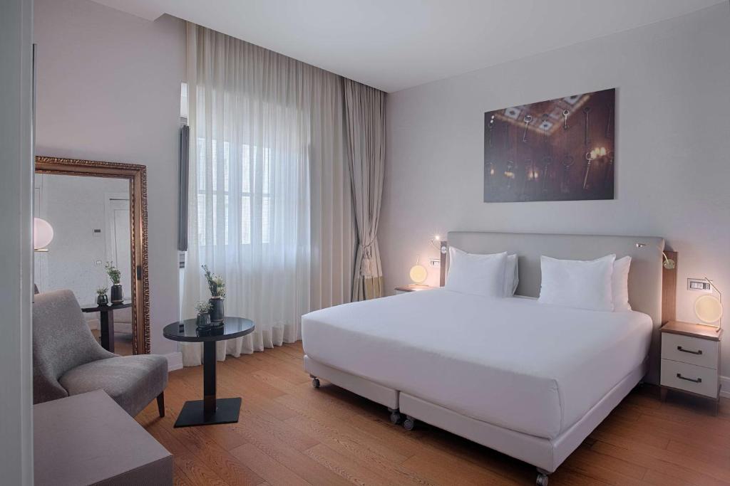 a hotel room with a large bed and a large window at NH Collection Firenze Porta Rossa in Florence