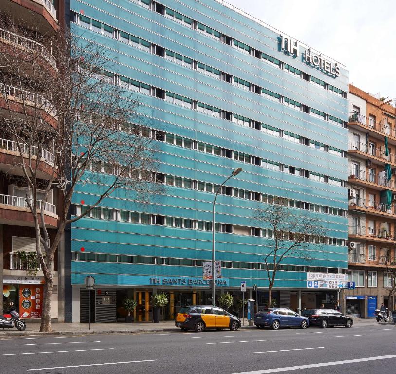 a blue building with cars parked in front of it at NH Sants Barcelona in Barcelona