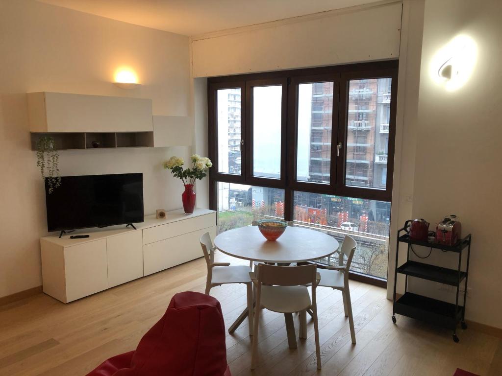 uma sala de estar com uma mesa e uma grande janela em Music House - Carozzi Apartments em Milão