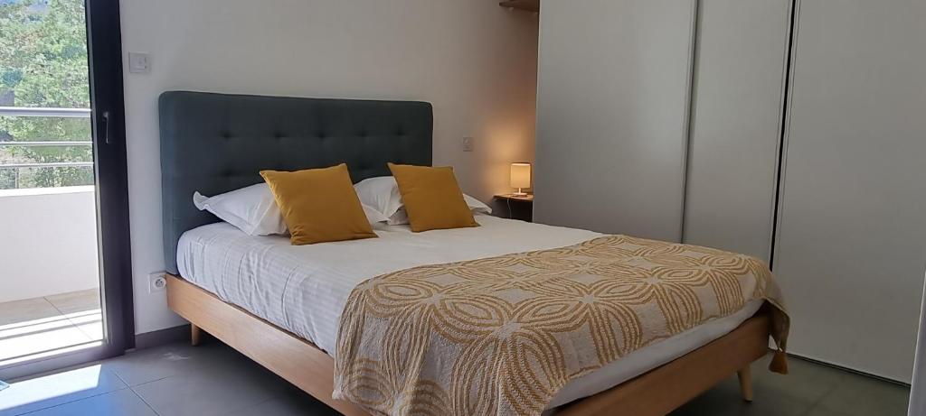 - une chambre avec un grand lit et des oreillers jaunes dans l'établissement Appartement de 2 chambres avec vue sur la mer et wifi a Porto Vecchio a 5 km de la plage, à Porto-Vecchio