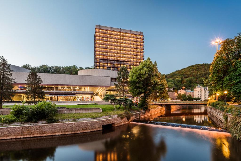 a building next to a river in front of a building at Hotel Thermal in Karlovy Vary