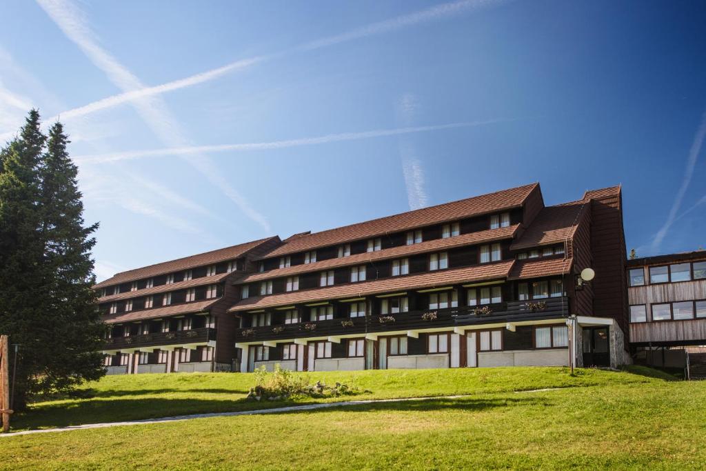 an office building with a green lawn in front of it at Rogla – Hotel Rogla in Resnik