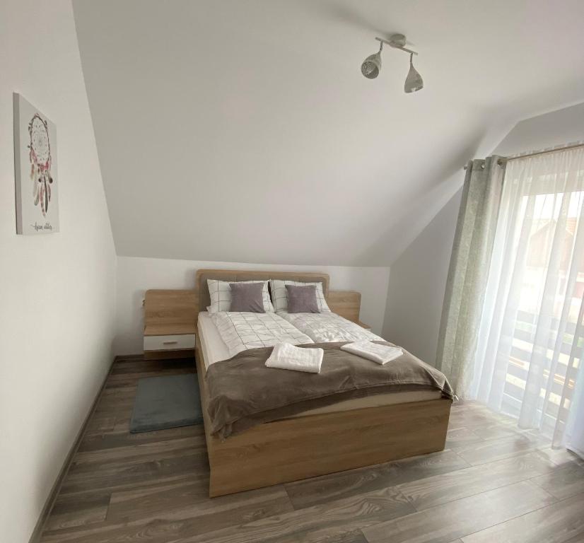 a white bedroom with a bed and a window at FENYŐ APARTMAN House I in Odorheiu Secuiesc