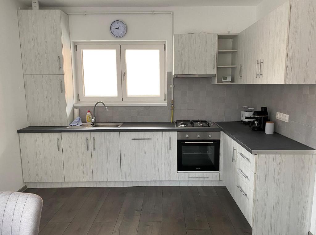 a kitchen with white cabinets and a sink and a window at FENYŐ APARTMAN House I in Odorheiu Secuiesc
