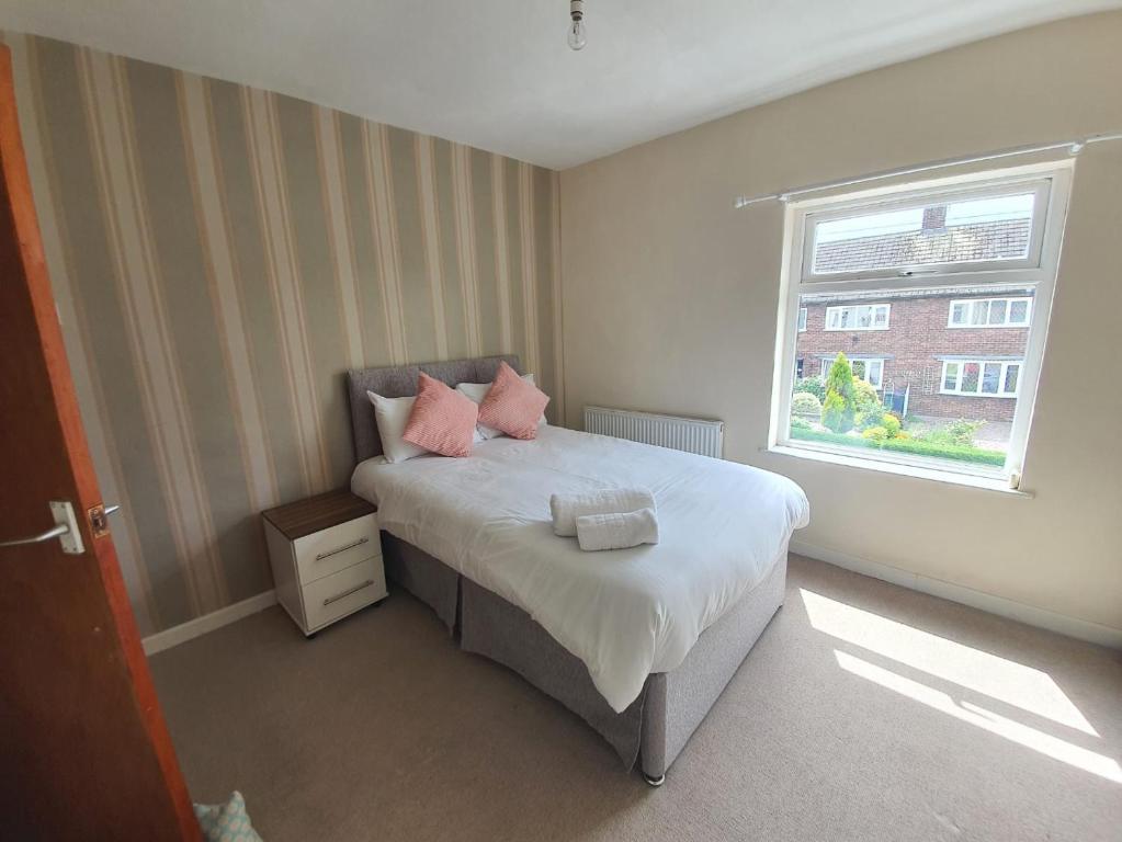 Un dormitorio con una cama con almohadas rosas y una ventana en Halmers House, en Audley