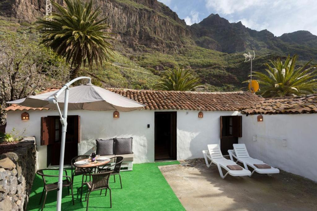 een patio met een tafel en stoelen en een huis bij Traditional Canary Cottage in Masca in Masca
