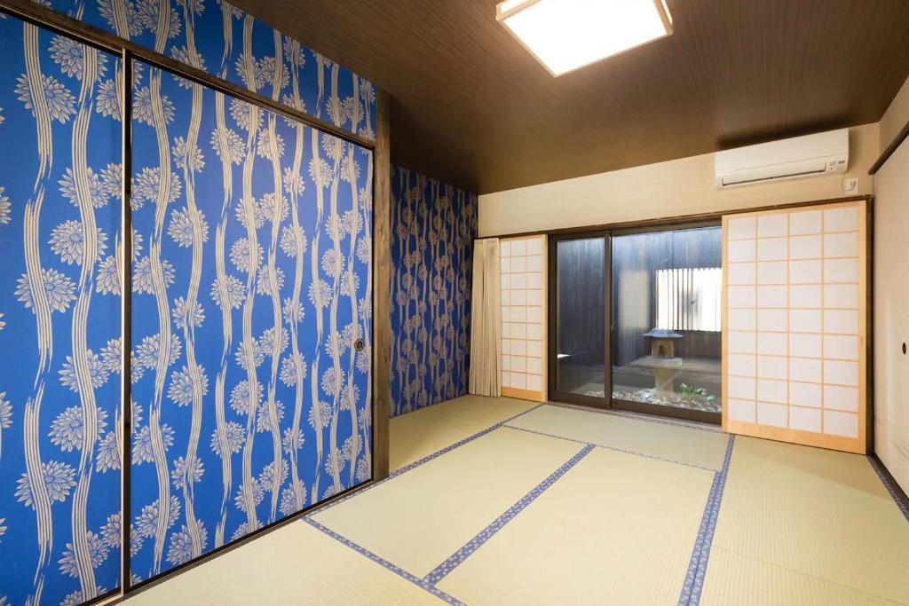 京都市にあるDaisenji Lodge Ing 藍 地下鉄鞍馬口駅から徒歩1分の青と白の壁紙を用いた窓のある客室です。