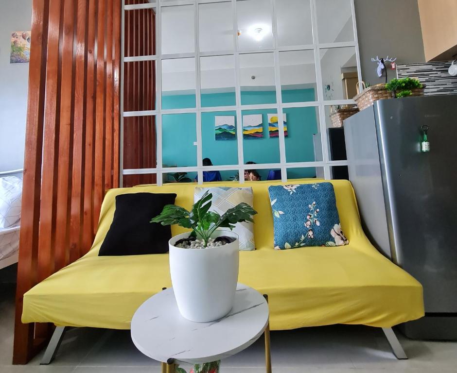 eine gelbe Couch mit einer Pflanze auf dem Tisch in der Unterkunft Stylish New Unit w/ Balcony at Fern Residences in Manila