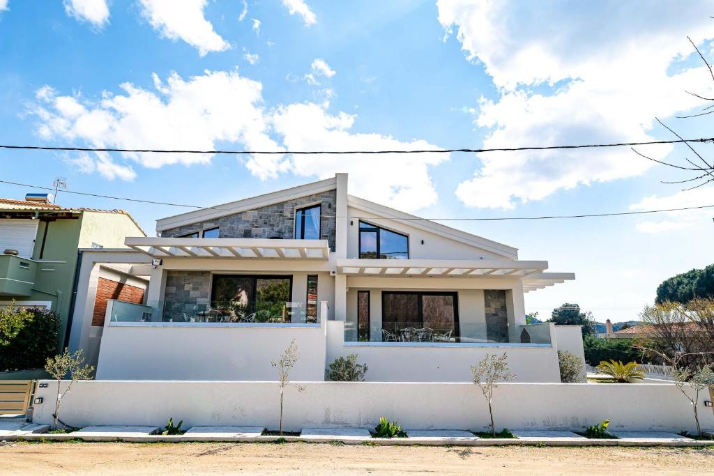 a house with a white fence in front of it at Filos Suites in Iraklitsa