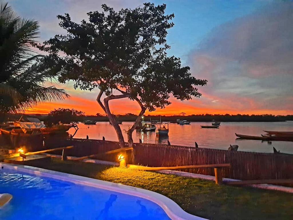 a swimming pool with a sunset in the background at Casa Valentine Pousada Itacaré in Itacaré