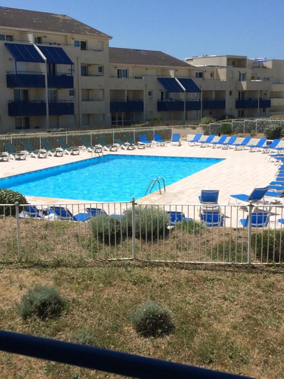 a large swimming pool with chairs and umbrellas at APPARTEMENT VUE OCEAN ET PISCINE in Lacanau