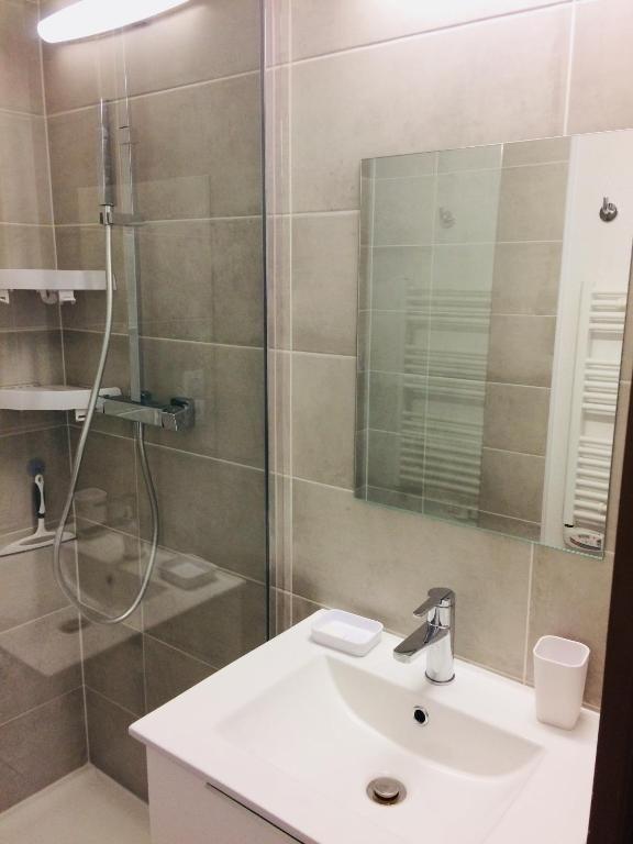 a bathroom with a white sink and a shower at APPARTEMENT VUE OCEAN ET PISCINE in Lacanau