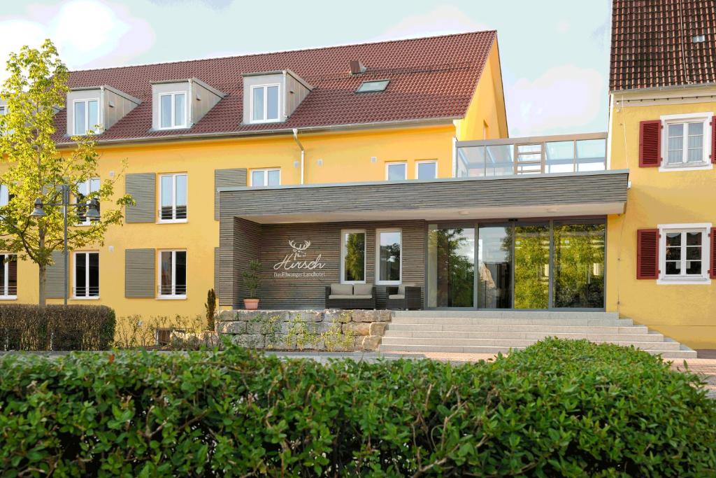 una casa amarilla con una escalera delante de ella en Hirsch - Das Ellwanger Landhotel, en Ellwangen