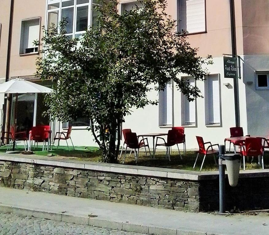 stół i krzesła oraz drzewo przed budynkiem w obiekcie Pensión-Albergue Puente Ribeira w mieście Sarria