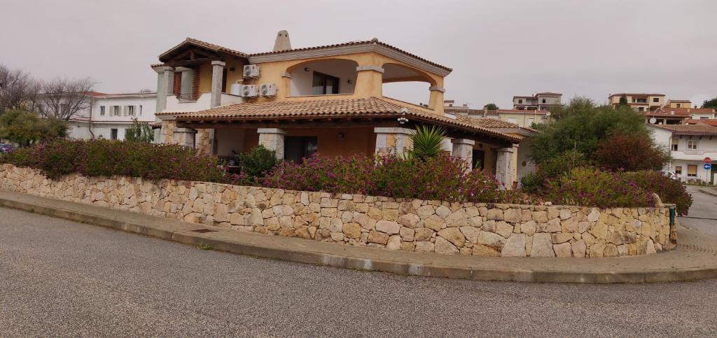 a house behind a stone wall in front of a street at villetta con terrazza in Posada
