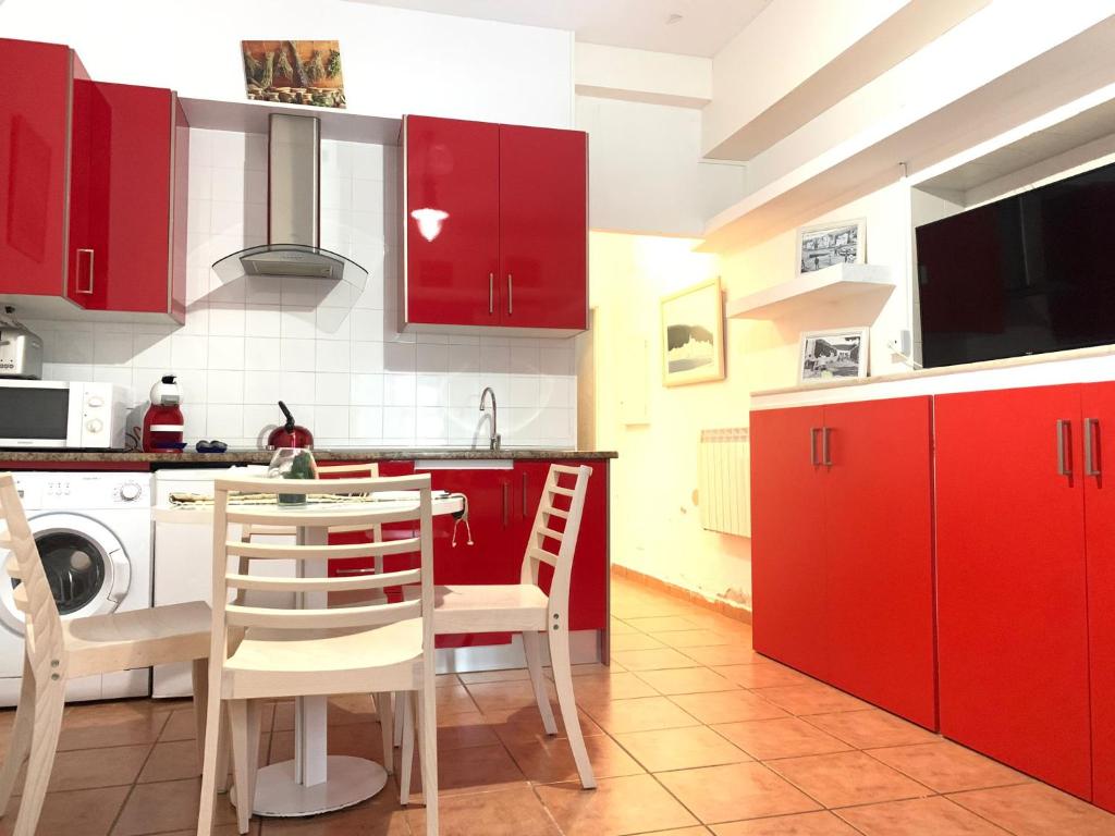 eine Küche mit roten Schränken sowie einem Tisch und Stühlen in der Unterkunft Apartament Cadaqués, Casa Nou 1935 in Cadaqués