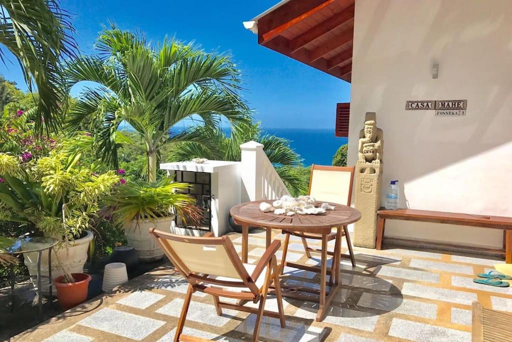 patio ze stołem i krzesłami oraz oceanem w obiekcie Hilltop South - Villa Bougainville w mieście Takamaka