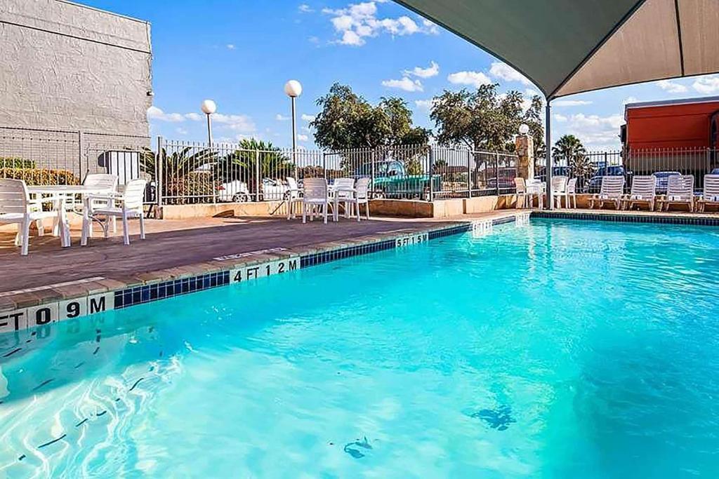 a swimming pool with blue water and white chairs at Travelodge by Wyndham San Antonio Downtown Northeast in San Antonio