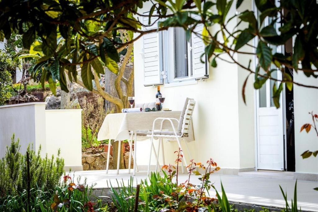 una mesa blanca y una silla frente a una casa blanca en Guest House Rooms Rose, en Molunat