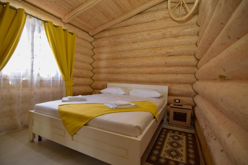 ein Schlafzimmer mit einem Bett in einem Blockhaus in der Unterkunft Cabanele Petran in Borşa