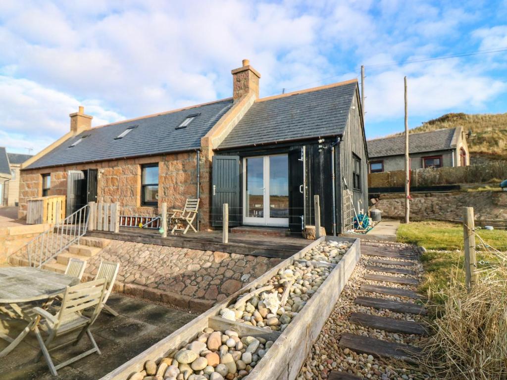 a stone cottage with a patio and a table at The Salmon Bothy in Peterhead