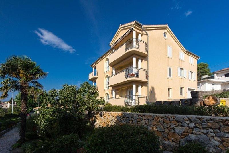 a large building on top of a stone wall at Marija F2 Apartment in Krk