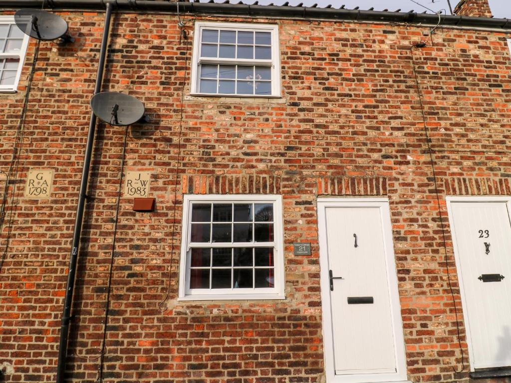 a brick building with white doors and windows at Keepers Cottage, 21 Coppergate in Nafferton