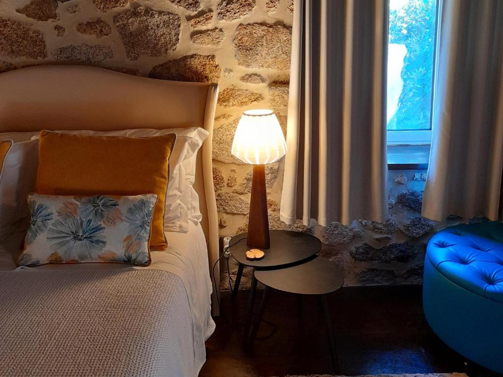 ein Schlafzimmer mit einem Bett und einer Lampe auf einem Tisch in der Unterkunft Fragas do Lobo - Casa da Azenha in Castelo Novo