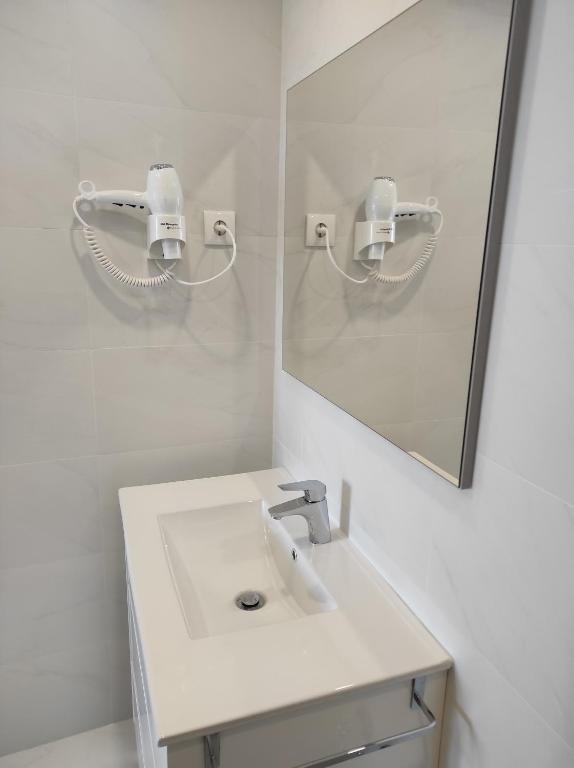 La salle de bains blanche est pourvue d'un lavabo et d'un miroir. dans l'établissement Casinha das Bonecas, à Constância