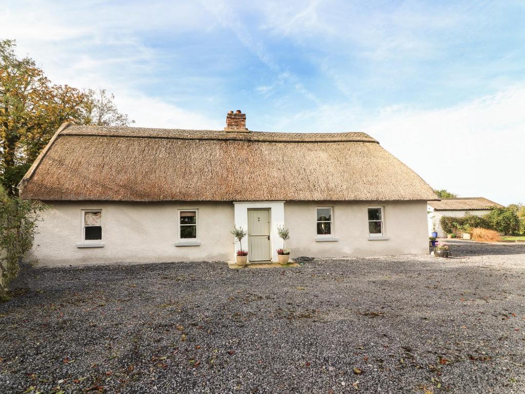 a small white house with a thatched roof at New Thatch Farm in Knocklong