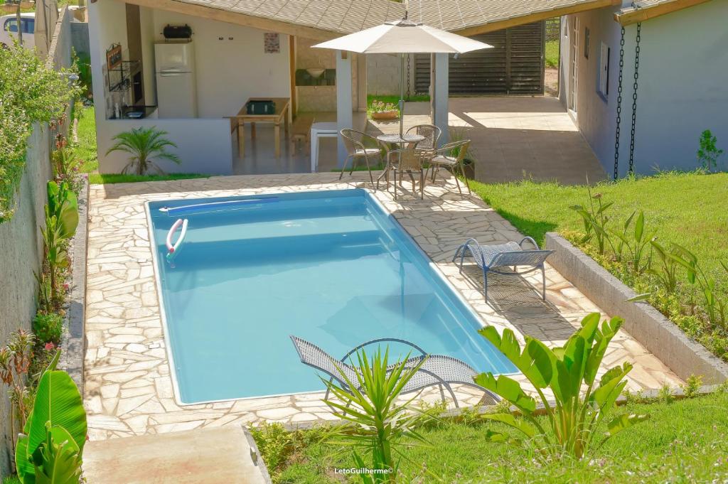 een zwembad in een tuin met een parasol bij Chácara Amigo Sol in Socorro