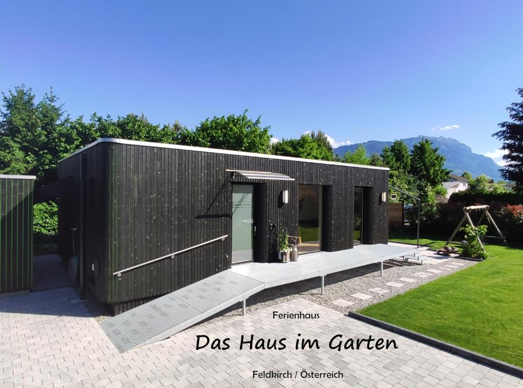 a black building with a door in a garden at Ferienhaus Haus im Garten in Feldkirch