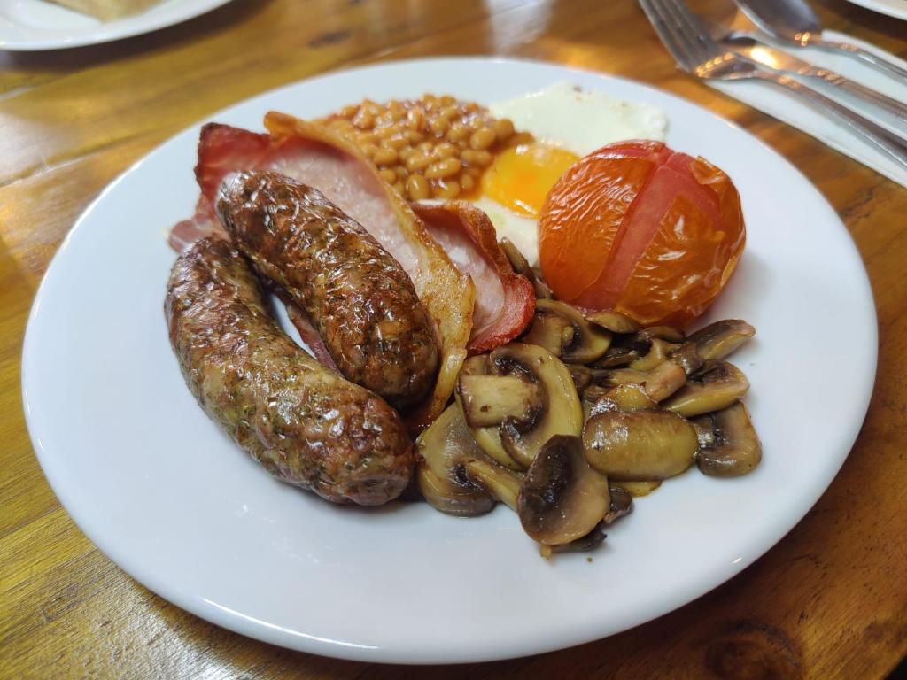 a plate of food with sausage eggs mushrooms and tomatoes at Woolpack Inn in Chichester