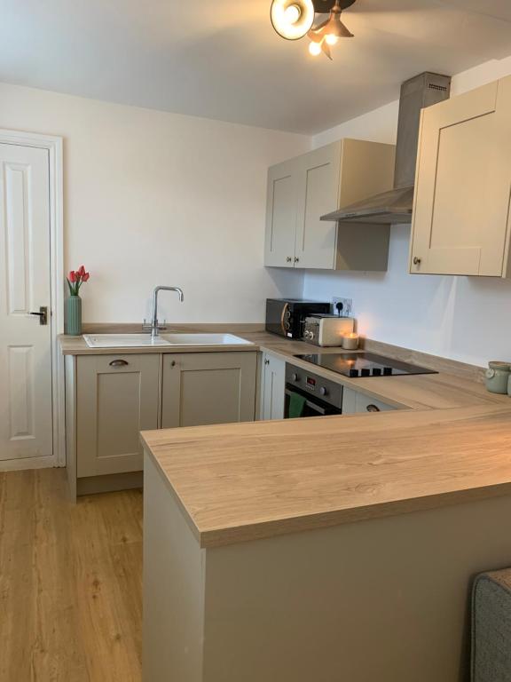 uma cozinha com armários brancos e uma bancada em Cosy ground floor Flat - Kendal Lake District with bike storage em Kendal