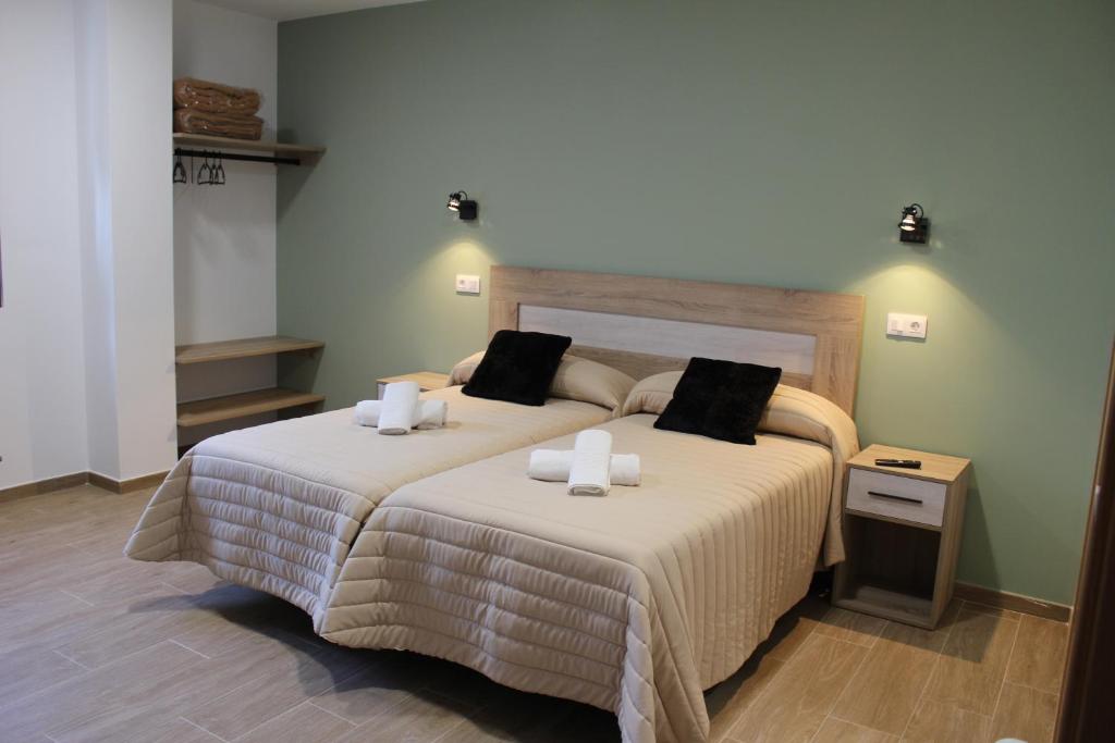 een slaapkamer met een groot bed met 2 kussens bij Pensión Albergue O Pedregal in Lourenzá