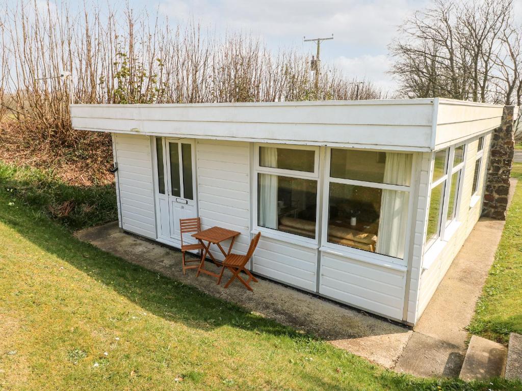 a small white shed with a table and chairs at Puffin Chalet in Roch