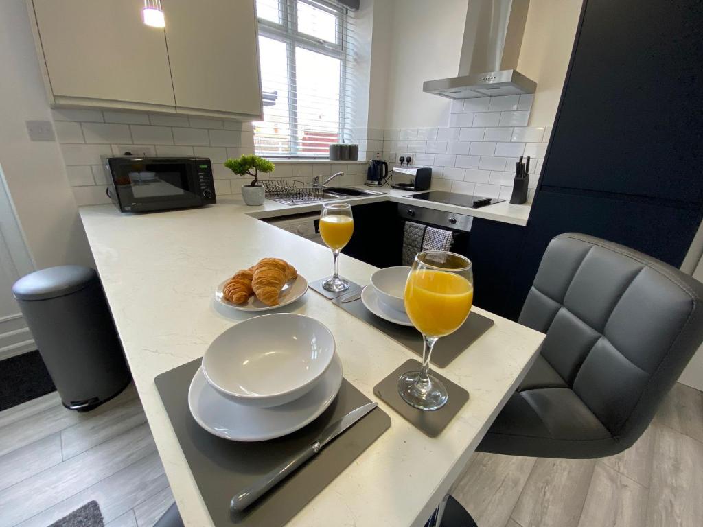 una cocina con 2 vasos de zumo de naranja y cruasanes en HU-Thirteen Apt One - Sleeps 4 en Hessle