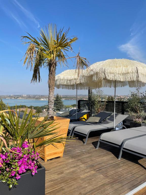 eine Terrasse mit einem Haufen Betten und Sonnenschirmen in der Unterkunft Plaza Lago di Garda in Peschiera del Garda