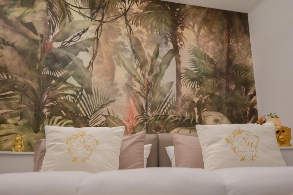 a bed with pillows in front of a floral wall at NM Luxury Suites in Pompei