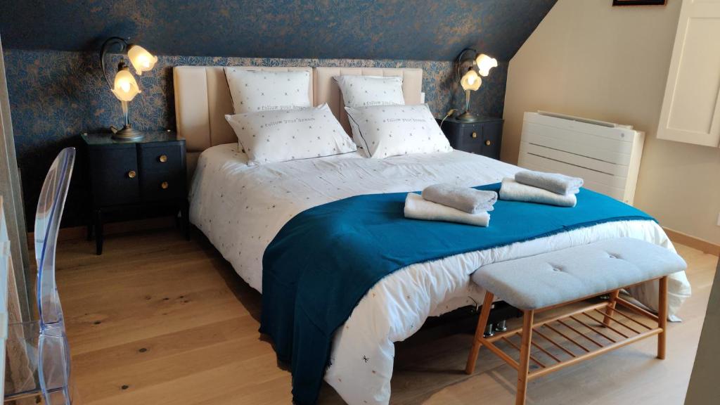 een slaapkamer met een groot bed en een blauwe deken bij Les coquelicots - Chambre Marie in Houdan