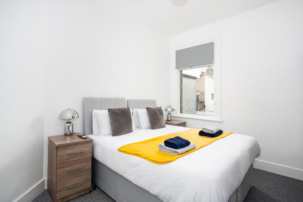 a bedroom with a bed with a yellow blanket on it at The Chase by Sorted Stay in Southend-on-Sea