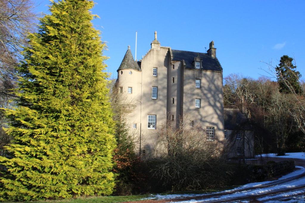 un vecchio castello con un albero in primo piano di West Wing Lickleyhead Castle a Auchleven