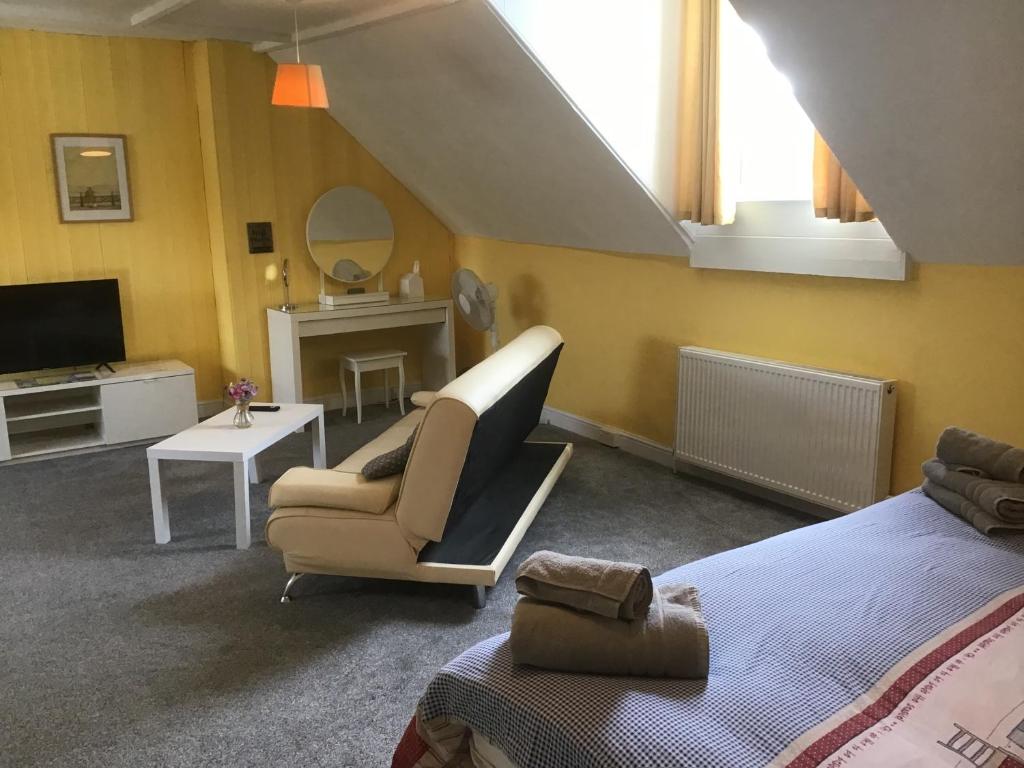 a bedroom with a bed and a chair and a television at Torwood House in Penzance