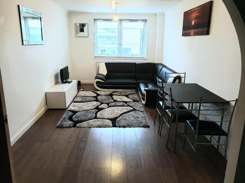 a living room with a black couch and a table at Spacious modern flat in Luton town centre in Luton