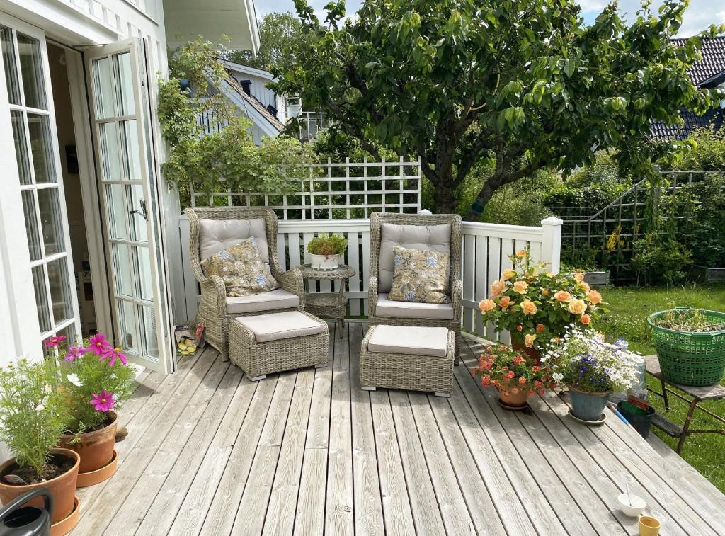 a patio with two chairs and a table and flowers at Nice and comfortable villa at the historic Naset in the Gothenburg archipelago in Västra Frölunda