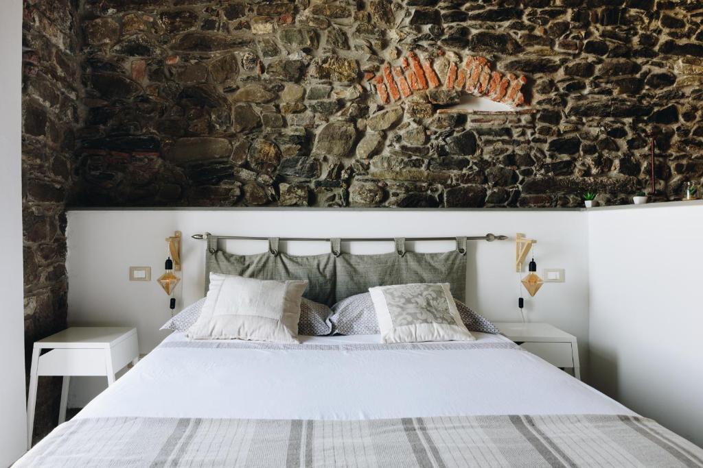 een slaapkamer met een wit bed en een stenen muur bij Punto Zero Suite in Corniglia